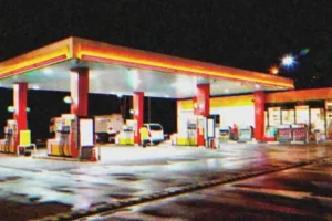 A koszos idős hölgy berohan a benzinkútra egy esős éjszakán, segítségért kiabálva